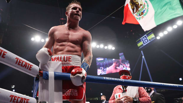 Canelo Álvarez celebra triunfo con bandera de México en el fondo.
